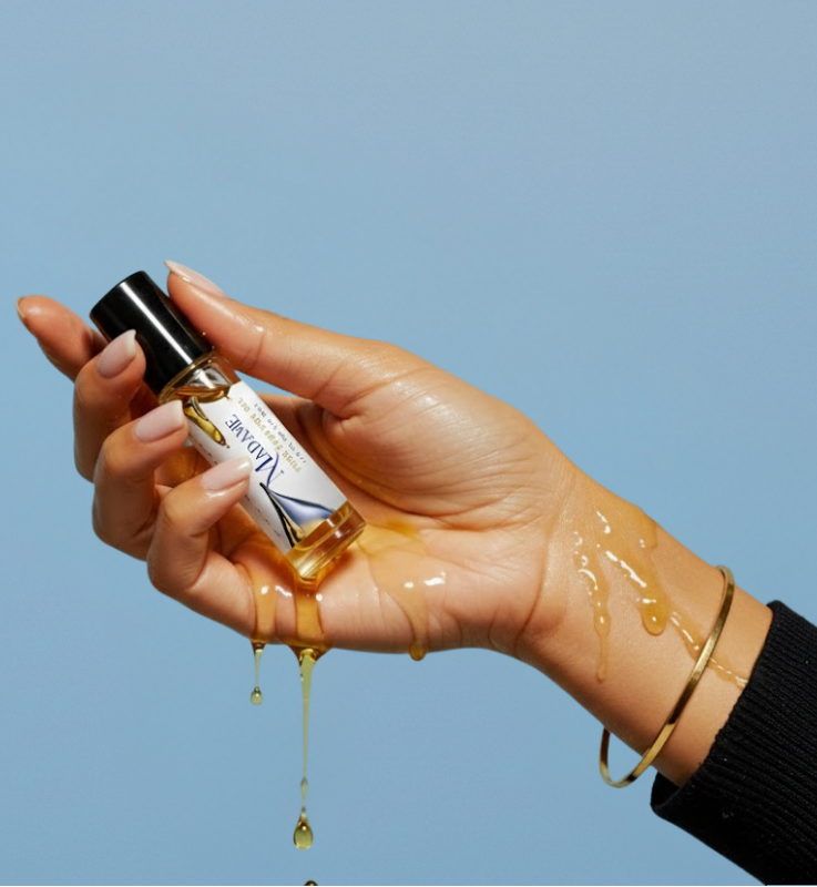 HauteBlends fine fragrance perfume oil concentrate alcohol free in a travel friendly / tsa approve 10ml rollerball with golden oil dripping on hand. 